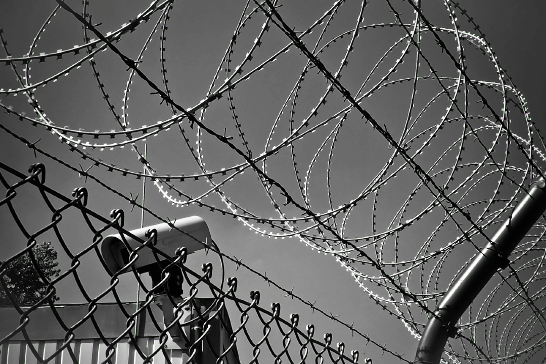 Barbed wire fence and security cameras in front of a building